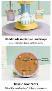 Close-up of wooden music box with miniature teapot charms and metal wind-up key base