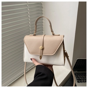 Detail of minimalist two-tone handbag with golden round clasp and elegant hand strap