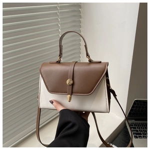 Detail view of contrast color stitching and gold buckle on a retro crossbody bag