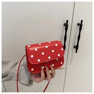 Close-up of a red mini crossbody bag with white polka dots on glossy leather material