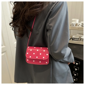 Detail view of retro red polka dot crossbody bag on model with vintage flap design