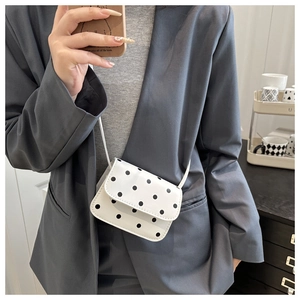 Mirror selfie showing a white polka dot mini crossbody bag with sleek shoulder strap