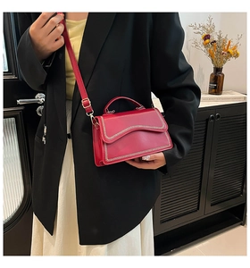 Détail du sac à bandoulière en cuir rouge avec bordure ondulée tressée sur un modèle