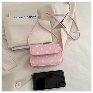 Mini pink polka dot handbag shown next to a smartphone to demonstrate portable size