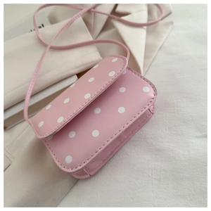 Detail of pink polka dot mini crossbody bag with fine stitching on an off-white blazer