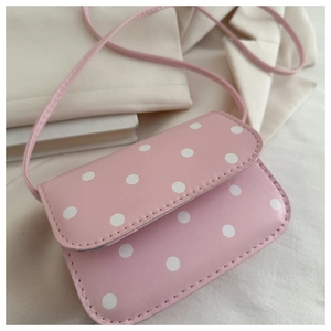 Detail of pink polka dot handbag with PU leather texture on cream blazer background