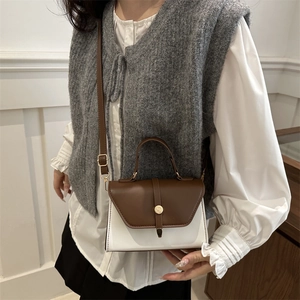Minimalist white and brown patchwork crossbody bag with gold buckle on a stylish model