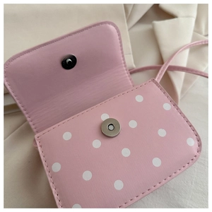 Detail of pink polka dot crossbody bag with silver magnetic snap and flap closure