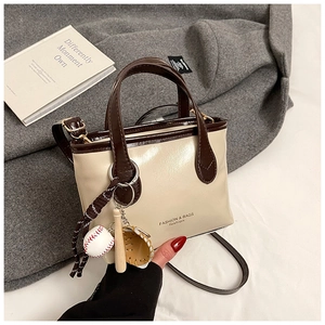 Detail of a two-tone mini tote bag with baseball charms on a soft wool coat surface
