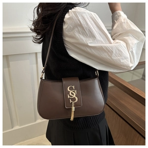 Detail van donkerbruine leren baguette tas met gouden SS-logo en metalen kwastjes