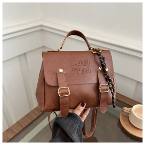 Detail eines braunen Vintage-Lederrucksacks mit Goldschnallen und Markenprägung