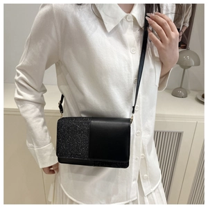 Close-up of black crossbody bag featuring sequin and matte leather patchwork design