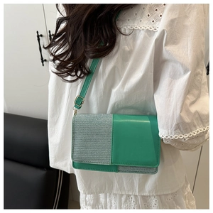 Detail of green and silver woven stitching on elegant crossbody bag with gold hardware
