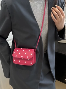 Vintage pink polka dot crossbody bag with thin strap over a grey blazer for women
