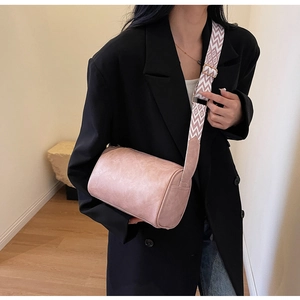 Détail du sac seau cylindrique rose poudré avec une large bandoulière tissée à motifs