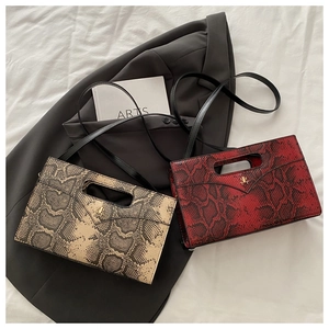 Macro detail of faux leather snake pattern texture and gold logo on the flap handbags