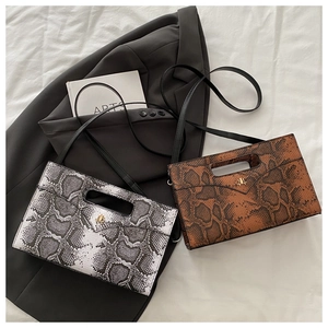 Detail of snake skin pattern envelope handbags with hollow handles and golden hardware