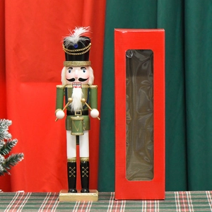 Green nutcracker soldier drummer with red window gift box on Christmas plaid tablecloth
