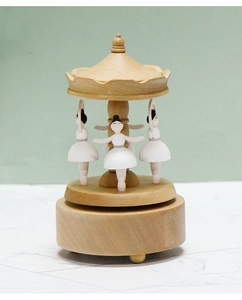 Close-up of wooden ballet music box featuring three dancers and natural wood grain