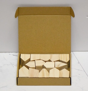 Detailed top view of natural wood house blocks in a minimalist brown cardboard box