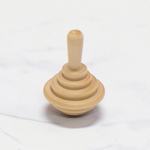 Minimalist wooden spinning top toy with natural grain on white marble background