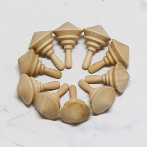 Set of 10 DIY unfinished wooden spinning tops arranged in a circular array on marble