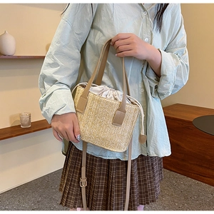 Detail of hand-woven straw tote with leather handles and white drawstring inner pouch