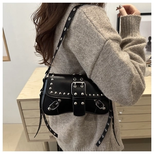 Detail of black punk leather bag featuring silver metal rivets and buckle straps