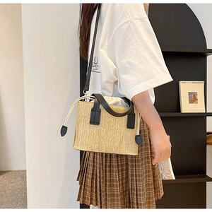 Detail of woven straw handbag with black leather straps and drawstring canvas inner pouch