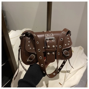 Détail d'un sac bandoulière en cuir marron avec œillets argentés et rivets punk