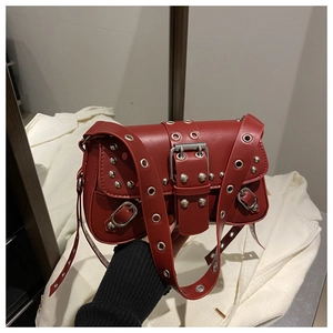 Détail du sac bandoulière punk rouge foncé avec œillets argentés et rivets métalliques chic