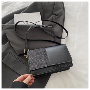 Détail du sac bandoulière noir aux textures mixtes avec boucle réglable en métal doré