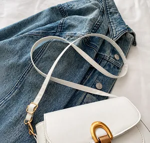 Detalle de bolso de silla en cuero sintético blanco con cierre de metal dorado en herradura