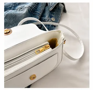 Detalle del bolso de hombro de cuero blanco con cremallera dorada y compartimento interior