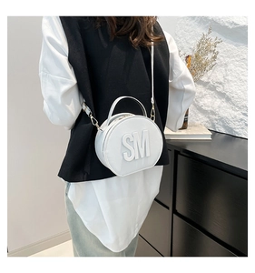 Detailed view of a white circular crossbody bag with embossed SM logo and gold zipper