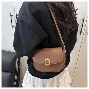 Detalle de un bolso de montura marrón con hebilla de herradura dorada y correa ajustable