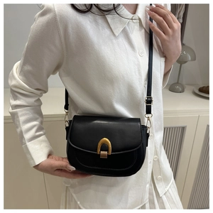 Détail d'un sac besace vintage en cuir noir avec une boucle dorée en forme de fer