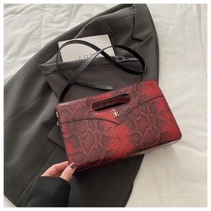 Macro detail of red and black snakeskin pattern leather clutch with gold metal logo