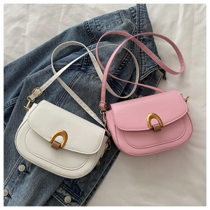 Gros plan de petits sacs à bandoulière blanc et rose avec boucle en fer à cheval dorée