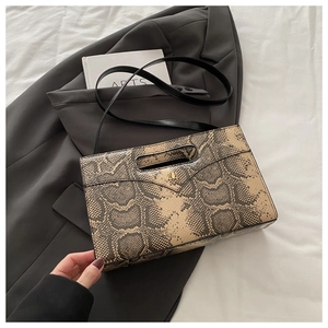 Macro detail of snakeskin pattern PU leather envelope bag with gold metal logo and handle