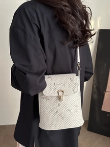 Sac à bandoulière tissé blanc cassé avec broderie florale et boucle dorée sur modèle