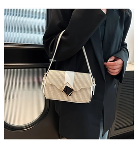 Détail du sac sous le bras en paille avec bordure en cuir blanc et boucle losange