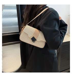Détail d'un sac à bandoulière en paille avec lanières en cuir sur un mannequin en blazer