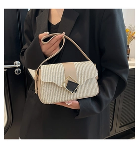 Détail d'un sac cabas en paille tissée avec rabat en cuir et boucle en métal