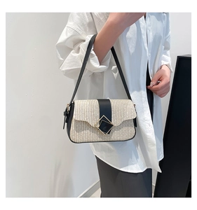 Détail du sac bandoulière en paille blanche avec bordure en cuir noir et boucles dorées