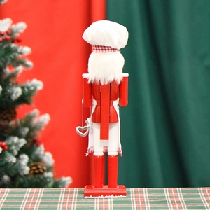 38cm classic red chef nutcracker wooden ornament standing by a decorated Christmas tree