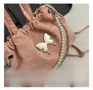 Detail of light pink drawstring bag with silver butterfly charm and pearl chain accent