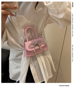 Mini sac rose avec nœud en strass et chaîne argentée porté par un mannequin