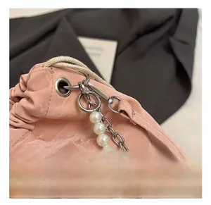 Detail of pink drawstring bag showing silver heart charm, pearl chain, and sturdy hook