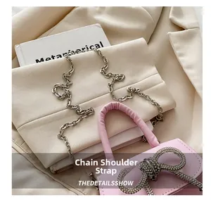 Detail van roze mini-handtas met strass-strik en elegante zilveren kettingriem